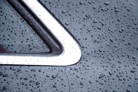 Water drops collect on top of metallic car surface