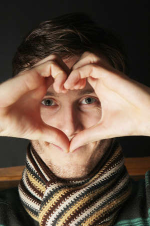 Young and handsome man makes a heart sign with his hands.