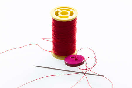 Button with two holes. Thin red thread.