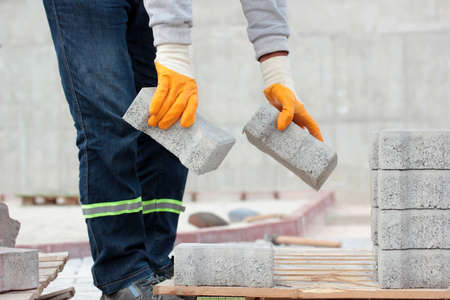Paving stone worker is putting down pavers during a construction of a city street.