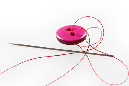 two thread holes, pink button, needle and threadの写真素材