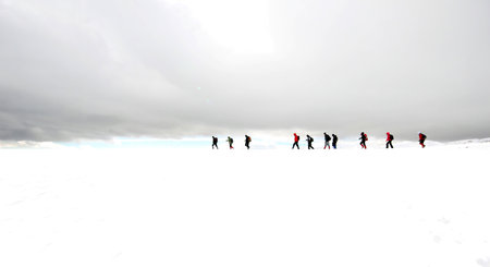 Group of mountaineers walking trough the mountains covered with snow.の写真素材