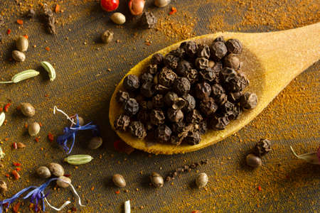 Black peppercorns on wooden spoon