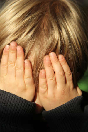 boy with blond hair covering his face