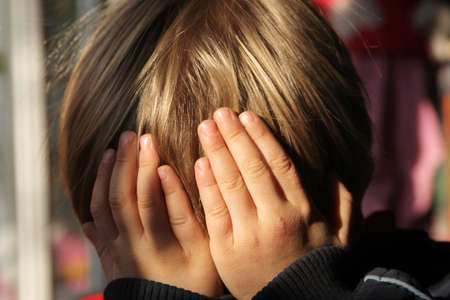 boy with blond hair covering his faceの写真素材