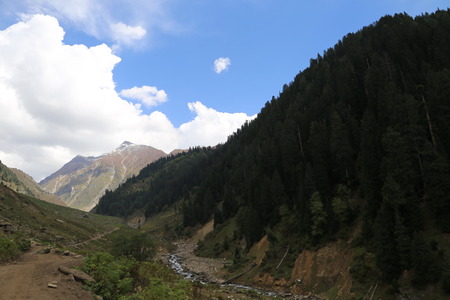 Small lake passing through the edge of mountain under blue skyの写真素材