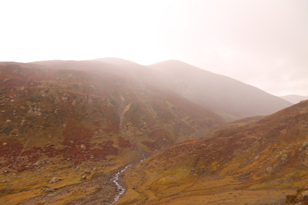 View of stream flowing through between the reddish mountainの写真素材