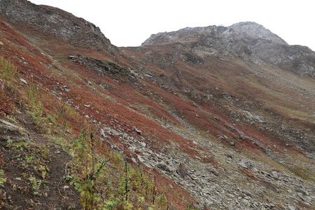 Mountains in autumn with brown and reddish grass under cloudy skyの写真素材