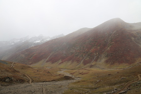 Mountains in autumn with brown and reddish grass under cloudy skyの写真素材