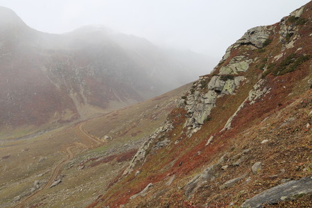 Mountains in autumn with brown and reddish grass under cloudy skyの写真素材