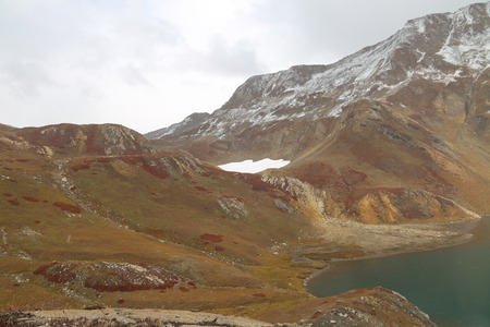 Mountain covered by glacier and view of amazing lake under dark cloudsの写真素材