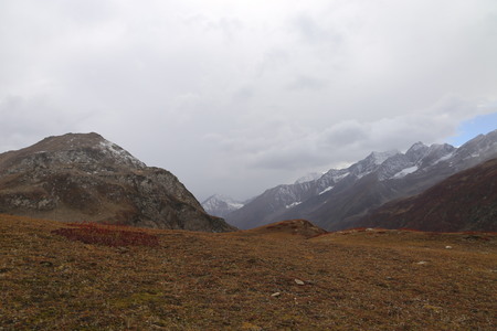 Mountains in autumn with brown and reddish grass under cloudy skyの写真素材