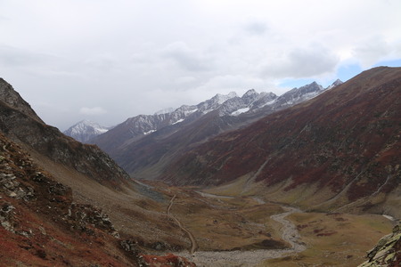 Mountains in autumn with brown and reddish grass under cloudy skyの写真素材