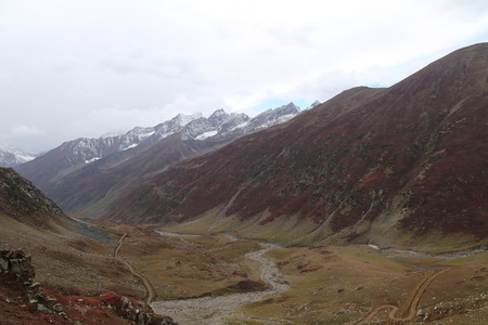 Mountains in autumn with brown and reddish grass under cloudy skyの写真素材