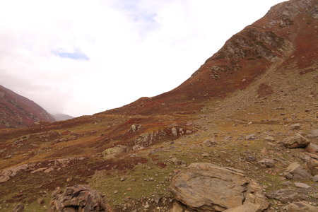 Mountains in autumn with brown and reddish grass under cloudy skyの写真素材