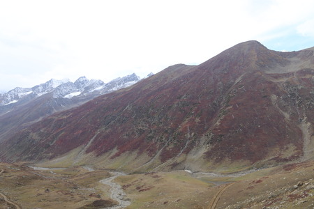 Mountains in autumn with brown and reddish grass under cloudy skyの写真素材