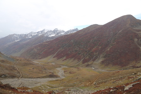 Mountains in autumn with brown and reddish grass under cloudy skyの写真素材