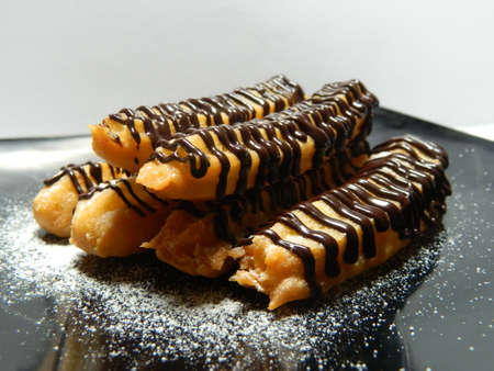 Churro or spain doughnut topping with fine granulated sugar and melted chocolate