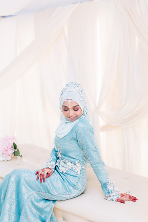 Portrait of Malaysian Muslim woman in wedding dress sitting and posing on bridal daisの写真素材