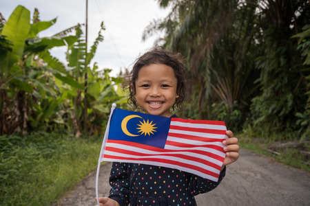 Portrait of young joyful girl with Malaysia flag. Merdeka theme concept. Malaysia's Independence Day. Selective focus.の写真素材