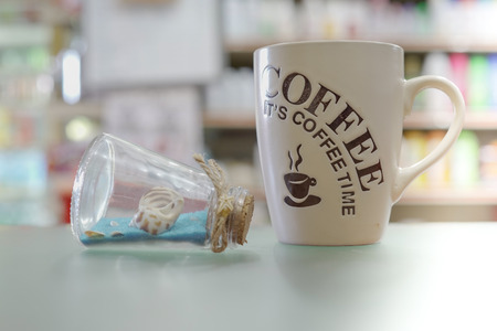 Mug of coffee with text 'It is coffee time' and beach ornament. Relaxing, vacation, travel ideas concept. Selective focus.の写真素材
