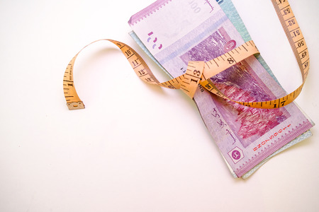 Banknotes of Ringgit Malaysia tied with measurement tape on white background isolated, selective...