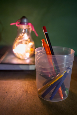 Creative layout of flat lay made of school accessories or student equipment includes books, pencil, alarm clock and ornaments on green and wood background. Selective focus. Educational, student life ideas concept.の写真素材