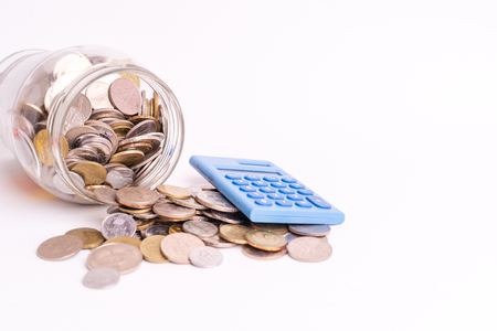Coins in glass jar with blue mini calculator on white background isolated. Financial and economy concept.の写真素材