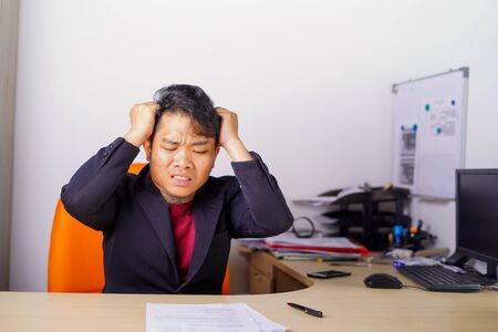 Young Asian man stressed, headache in office, facing many problem.