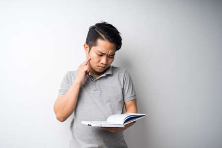 Portrait of Asian man holding book with face expression