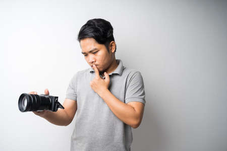 Young Asian man face expression with dslr or mirrorless camera. Photography, creative industry. Isolated selective focus.の写真素材