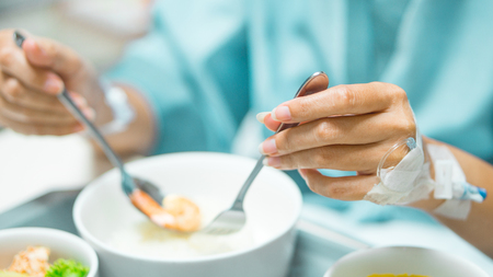 Patient and hospital concept - Asia woman patient hand with iv solution eating food for patient on bed in hospital and copyspaceの写真素材