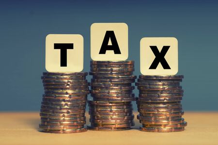 Tax Concept with tax word on stacked gold coinsの写真素材