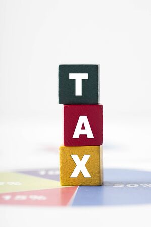 Tax Concept with colorful wooden block tax word on pie chartの写真素材