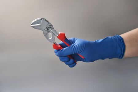 hand in red glove holds wrench toolの写真素材