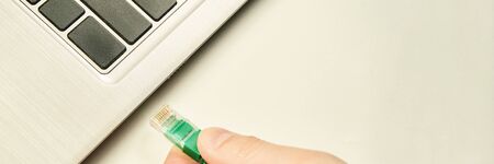 Hand holding lan cable with RG45 connector for plug to laptop
