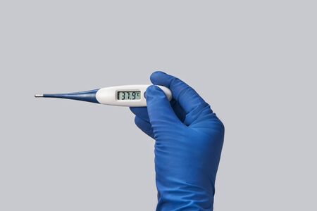 hand in blue glove holds thermometer high temperatureの写真素材