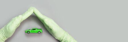 Hand in green glove defend toy car. Safety anti virus conceptの写真素材