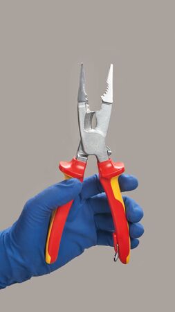 Hand in glove holds open pliers electricianの写真素材