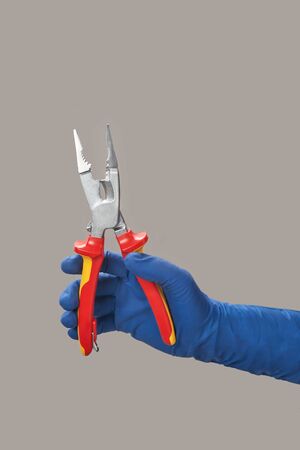 Hand in glove holds open electrician pliersの写真素材
