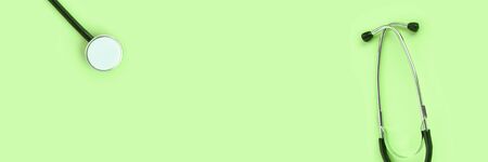 stethoscope lying on a green background. The concept of medical equipment instrument. heartbeat and breath check to doctor. horizontal banner. diagnose clinical research. Top view. Copyspace bannerの写真素材