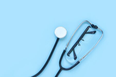 stethoscope and eyeglass lying on a blue background. The concept of medical equipment instrument. heartbeat and breath check to doctor. horizontal banner. diagnose clinical research. Copyspaceの写真素材