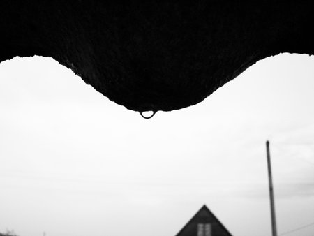 Black and white photo of a metal hook hanging from the roof.の写真素材