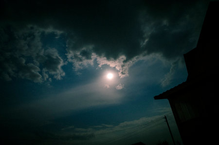 The moon shines through the clouds in the night sky.