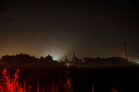 Night sky with stars and a church in the middle of the fieldの写真素材