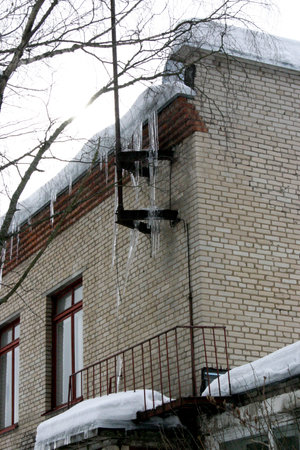 Icicles hang from the roof of a house in winter.の写真素材