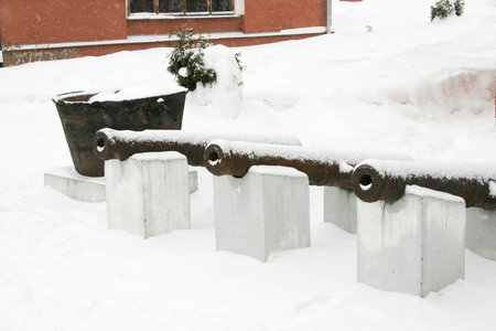 Snow-covered cannons in the courtyard of a residential building in winterの写真素材