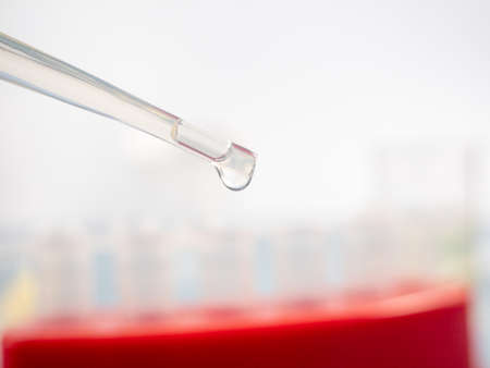 Analytical chemistry - sample being pipetted into test tube for analysis in laboratory.