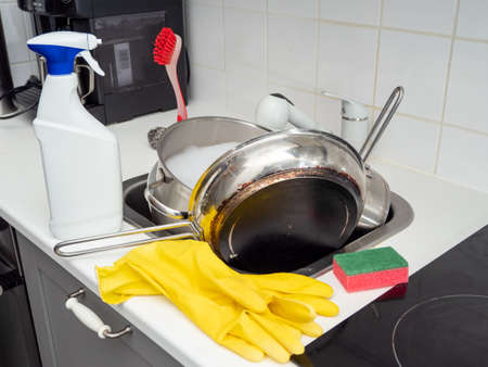 Washing dishes while cleaning the house. Kitchen cleaning. Dirty dishes.の写真素材