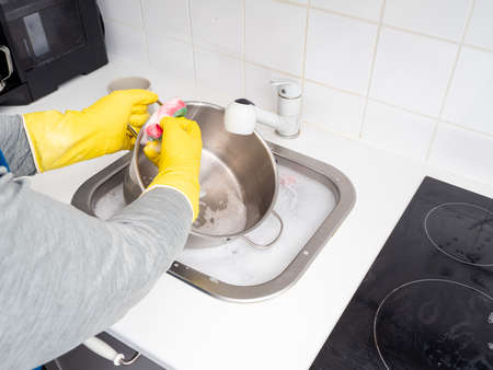 Washing dishes while cleaning the house. Kitchen cleaning. Dirty dishes.の写真素材